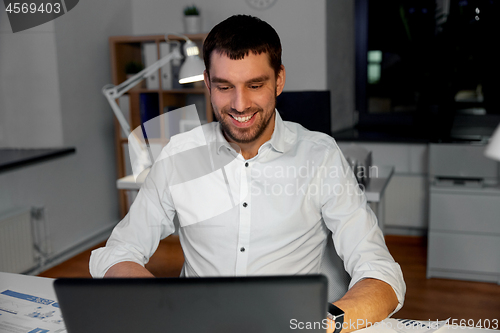 Image of businessman with laptop working at night office