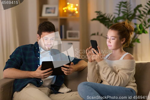 Image of couple with tablet computer and smartphone at home