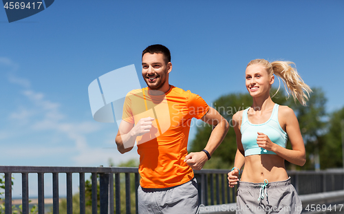 Image of couple with fitness trackers running along bridge