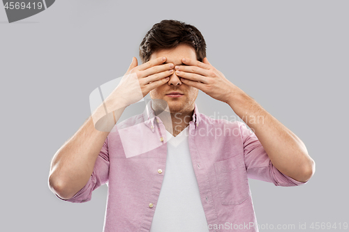 Image of man closing his eyes by hands over grey background