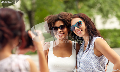 Image of woman photographing her friends in summer park