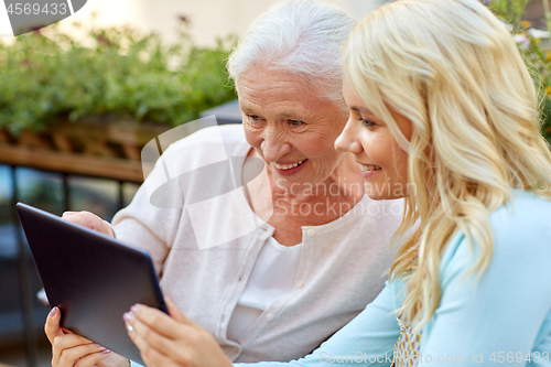 Image of daughter with tablet pc and senior mother outdoors