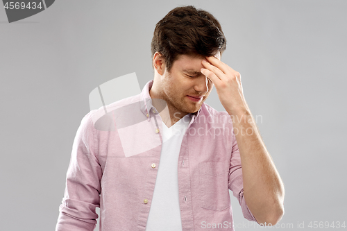 Image of unhappy young man suffering from headache