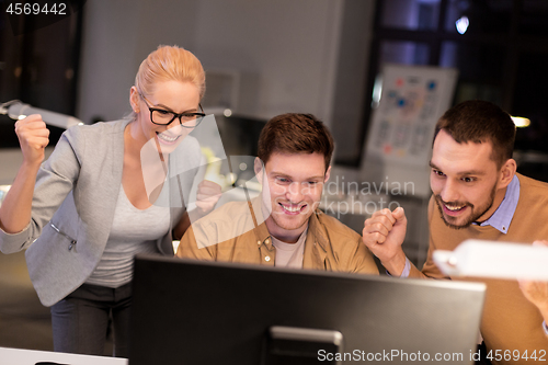 Image of business team celebrating success at night office