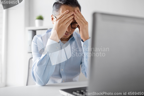 Image of stressed businessman with laptop working at office