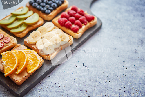 Image of Wholegrain bread slices with peanut butter and various fruits