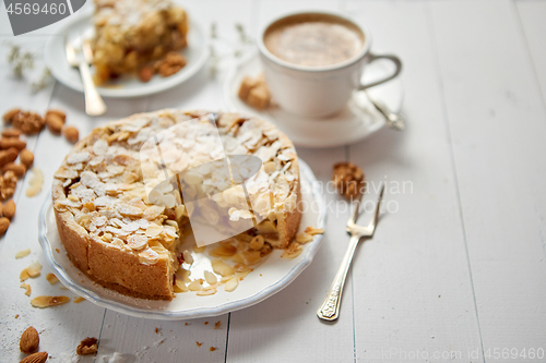 Image of Whole delicious apple cake with almonds served on wooden table