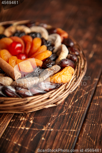 Image of Mix of dried fruits in a small wicker basket on wooden table