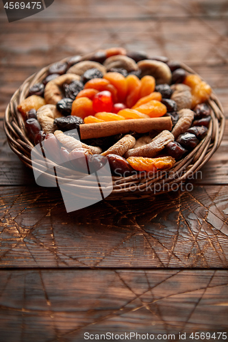 Image of Mix of dried fruits in a small wicker basket on wooden table