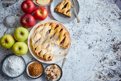 Image of Delicious apple pie cake with a fresh fruits, brown and powder sugar