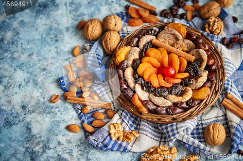 Image of Composition of dried fruits and nuts in small wicker bowl placed on stone table