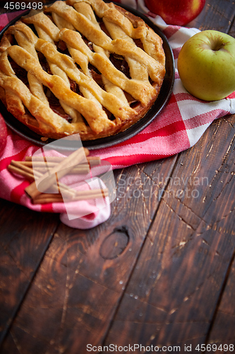 Image of Homemade pastry apple pie with bakery products on dark wooden kitchen table