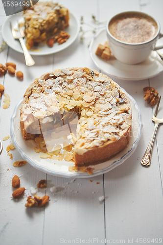 Image of Whole delicious apple cake with almonds served on wooden table