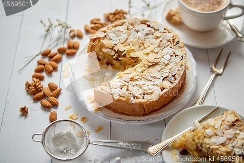 Image of Whole delicious apple cake with almonds served on wooden table