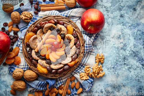 Image of Composition of dried fruits and nuts in small wicker bowl placed on stone table