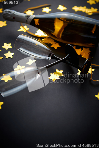 Image of Glasses and bottle of champagne with golden serpentines and confetti