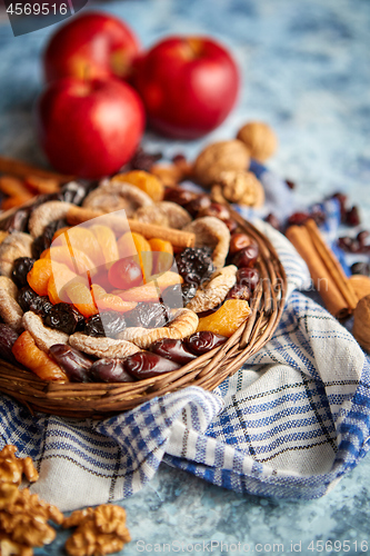 Image of Composition of dried fruits and nuts in small wicker bowl placed on stone table