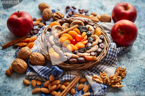 Image of Composition of dried fruits and nuts in small wicker bowl placed on stone table