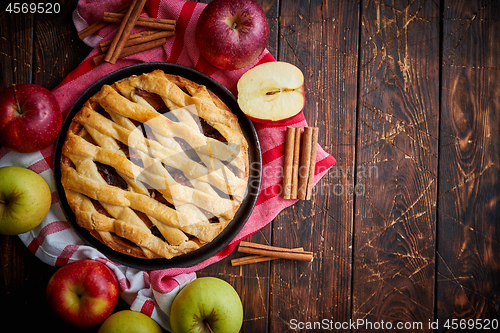 Image of Homemade pastry apple pie with bakery products on dark wooden kitchen table