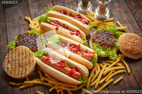 Image of Fastfood assortment. Hamburgers and hot dogs placed on rusty wood table