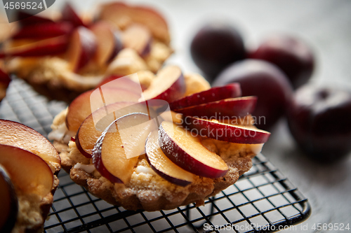 Image of Homemade crumble tarts with fresh plum slices placed on iron baking grill