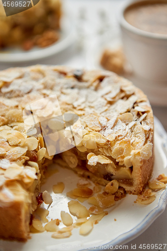 Image of Whole delicious apple cake with almonds served on wooden table