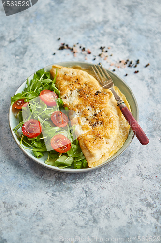 Image of Classic egg omelette served with cherry tomato and arugula salad on side