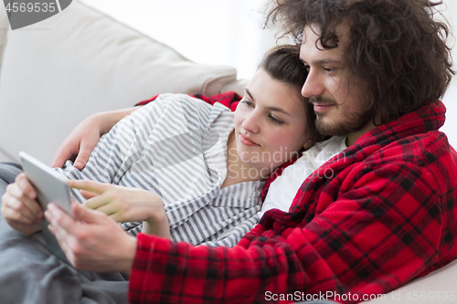 Image of couple relaxing at  home with tablet computers