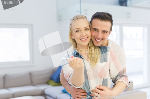 Image of couple showing small red house in hands