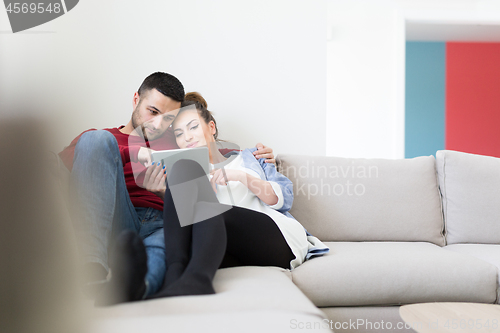 Image of couple relaxing at  home with tablet computers