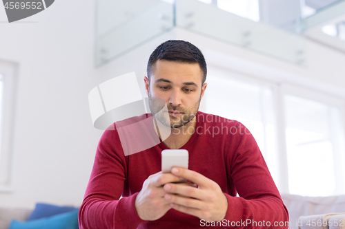 Image of young man using a mobile phone  at home