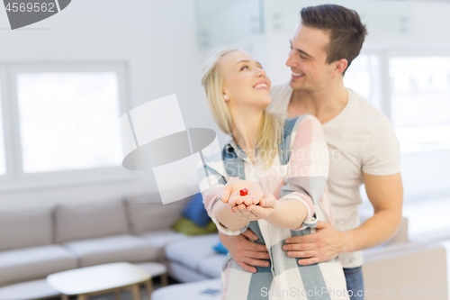 Image of couple showing small red house in hands