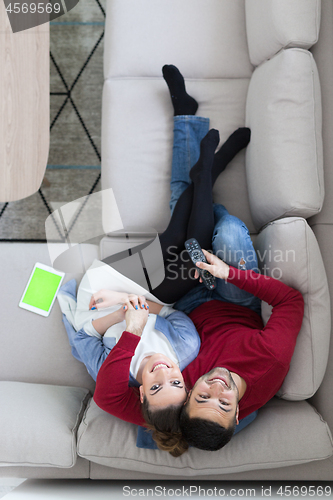 Image of Young couple on the sofa watching television top view