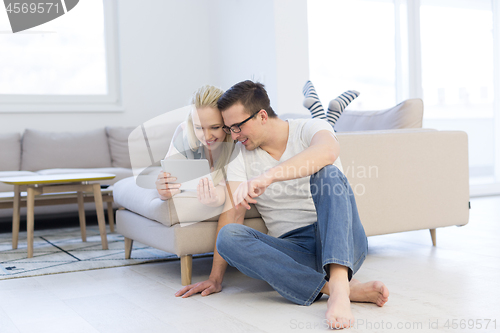 Image of couple relaxing at  home with tablet computers