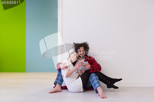 Image of Young Couple using digital tablet on the floor