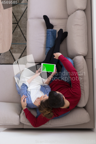 Image of couple relaxing at  home with tablet computers