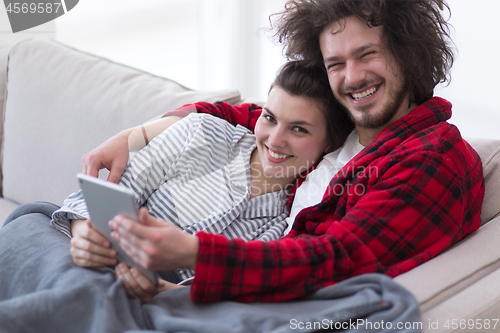 Image of couple relaxing at  home with tablet computers