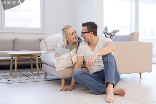 Image of couple relaxing at  home with tablet computers