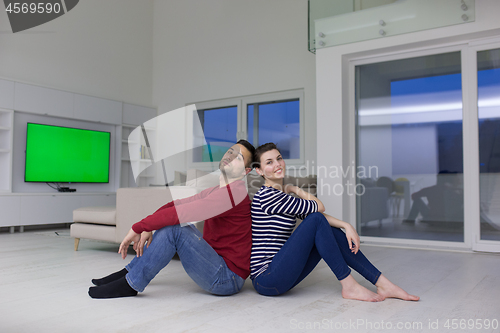 Image of young couple sitting with back to each other on floor