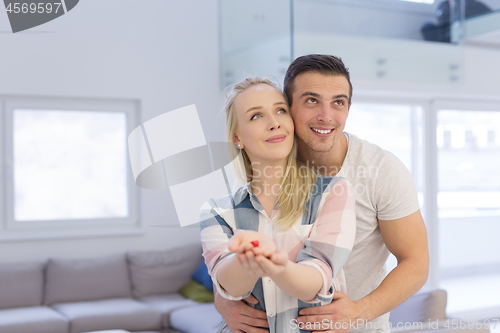 Image of couple showing small red house in hands