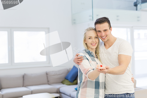 Image of couple showing small red house in hands