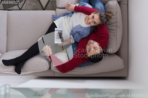 Image of couple relaxing at  home with tablet computers