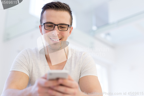 Image of young man using a mobile phone  at home