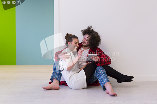 Image of Young Couple using digital tablet on the floor