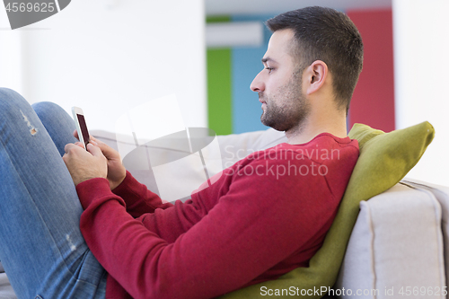 Image of young man using a mobile phone  at home