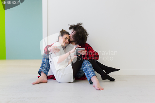 Image of Young Couple using digital tablet on the floor