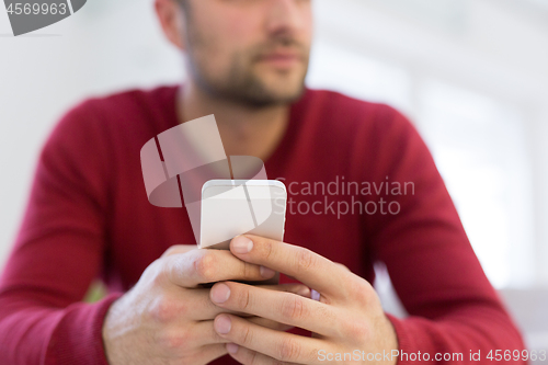 Image of young man using a mobile phone  at home