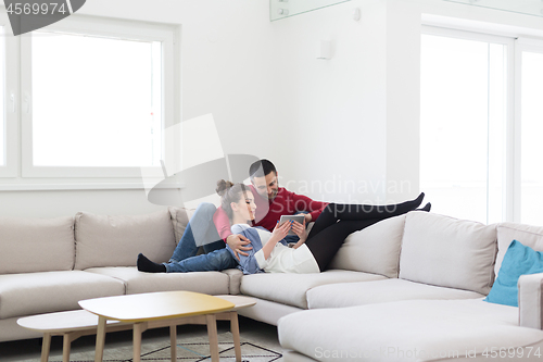 Image of couple relaxing at  home with tablet computers