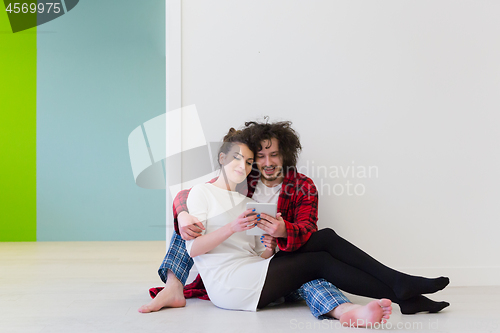 Image of Young Couple using digital tablet on the floor