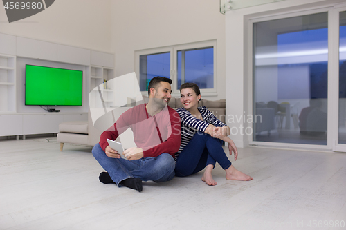 Image of Young Couple using digital tablet on the floor